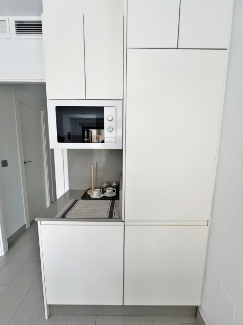 Moderno rincón de cocina blanco en apartamento de lujo en Fuengirola con microondas y estación de café