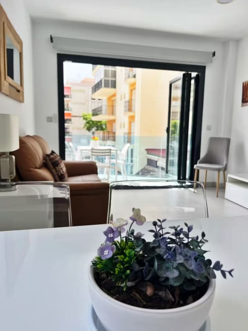 Apartamento de lujo en Fuengirola con sala moderna, sofá marrón y balcón con vistas a edificios coloridos