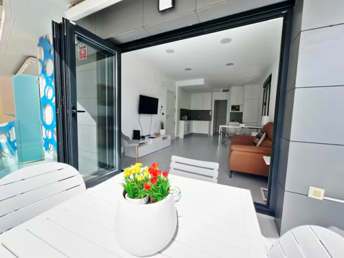 Apartamento de lujo moderno en Fuengirola con salón abierto, cocina y acceso a terraza mediante puertas de cristal