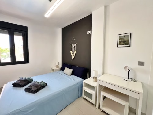 Lujoso dormitorio moderno en Fuengirola con cama matrimonial, pared de acento oscuro, muebles blancos y decoración contemporánea