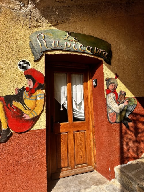 Entrée colorée du gîte Le Rupicapra à Roubion avec fresques éclatantes et porte en bois