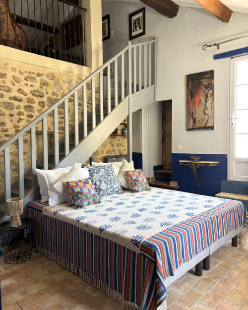 Chambre au Domaine Du Commandeur avec lit, escalier blanc, linge de lit à motifs et murs en pierre