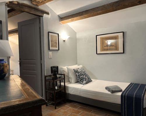 Chambre élégante au Domaine Du Commandeur, Mondragon avec lit blanc, poutres apparentes et œuvres d'art encadrées