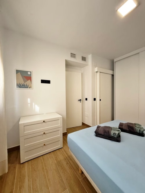 Dormitorio moderno de apartamento en playa de Fuengirola con cómoda blanca, cama y puertas
