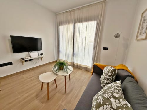 Moderno apartamento frente al mar en Fuengirola con sofá gris, pared de TV y balcón con vista al mar