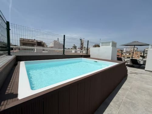 Piscina moderna en azotea con agua turquesa en apartamento frente al mar en Fuengirola, vistas al horizonte de la ciudad