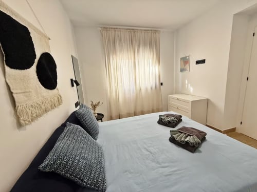 Dormitorio moderno de apartamento frente al mar en Fuengirola con cama de matrimonio, muebles blancos y decoración costera por Grupo Inmohouse