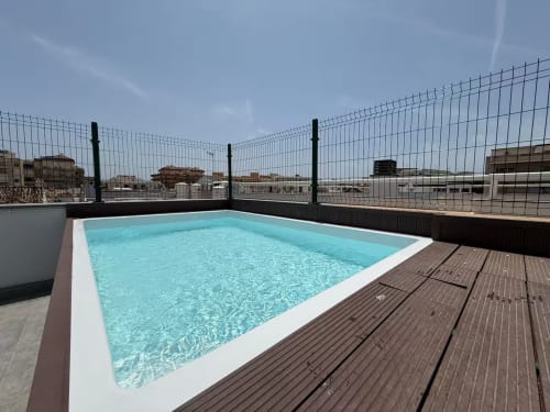 Piscina en la azotea con agua turquesa y vistas a la ciudad en apartamento frente al mar en Fuengirola