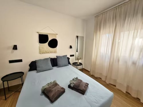 Moderno apartamento frente al mar en Fuengirola con dormitorio contemporáneo, almohadas a rayas y decoración minimalista en blanco y negro