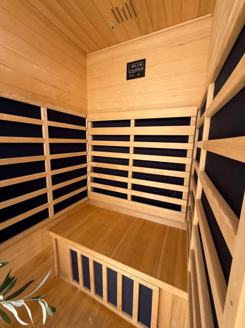 Interior de sauna infrarroja con bancos de madera y panel de control digital en apartamento de playa en Fuengirola