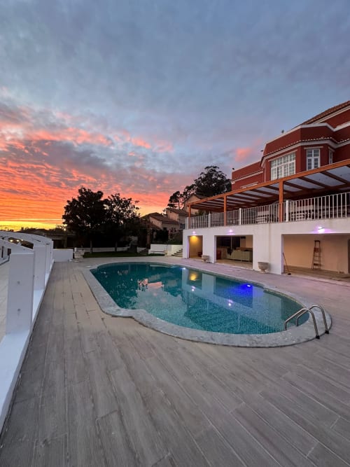 Piscina iluminada do Boutique Hotel Quinta dos Lobos ao pôr do sol em Sintra com vila de telhado vermelho