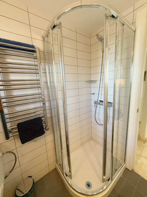 Moderno baño con ducha, azulejos blancos y toallero en apartamento de Fuengirola