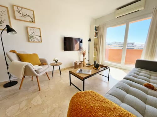 Moderno apartamento frente al mar en Fuengirola con vistas a la ciudad, mobiliario contemporáneo y luminosa sala de estar