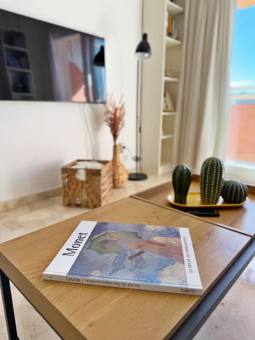 Moderno apartamento en primera línea de playa en Fuengirola con libro de arte Monet, decoración de cactus y vista al mar desde escritorio de madera