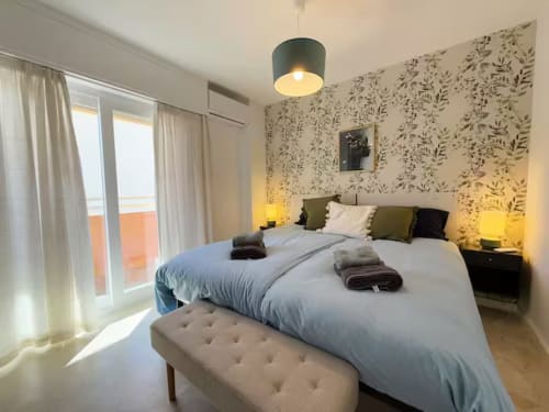 Moderno apartamento frente al mar en Fuengirola con cama matrimonial, papel pintado floral, balcón y vistas a la ciudad