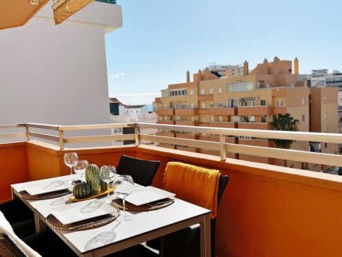 Balcón de apartamento frente al mar en Fuengirola con zona de comedor con vistas a edificios de terracota