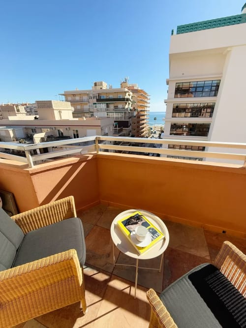 Balcón moderno de apartamento frente al mar en Fuengirola con vistas al océano, muebles de mimbre y vista al centro costero