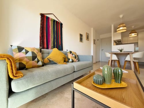 Moderno apartamento frente al mar en Fuengirola con sofá gris, toques amarillos y vista a la ciudad