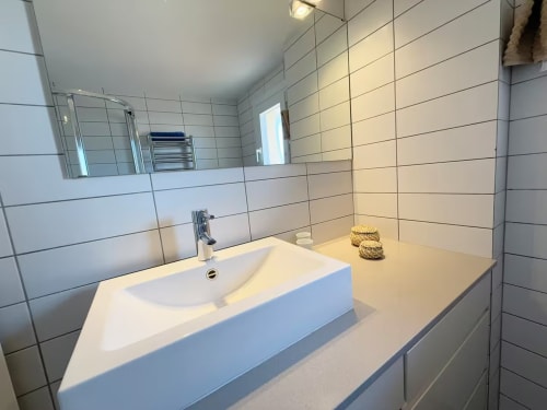 Moderno baño con lavabo blanco, paredes azulejeadas y espejo en apartamento de playa soleado en Fuengirola