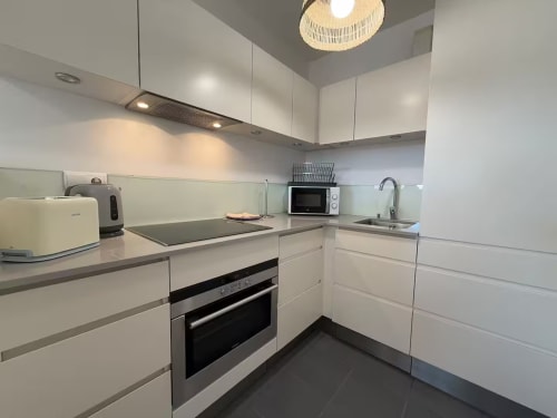 Cocina moderna blanca en apartamento frente al mar soleado, Fuengirola con electrodomésticos de acero inoxidable