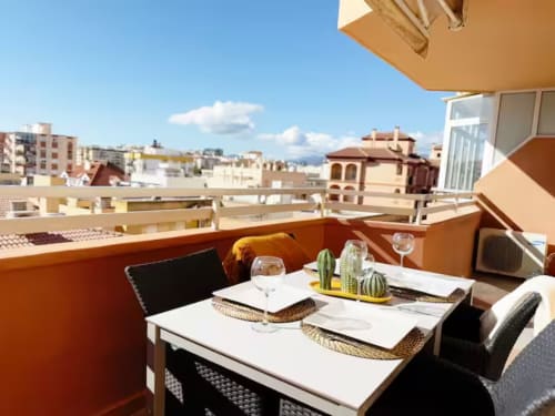 Terraza moderna de apartamento frente al mar en Fuengirola con zona de comedor y vista al horizonte de la ciudad
