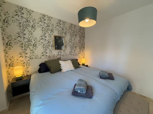 Moderno dormitorio soleado en Fuengirola con papel pintado botánico, cama doble e iluminación ambiental