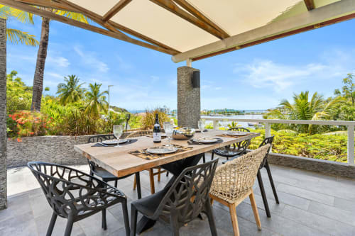 Terrasse de salle à manger extérieure de la villa Les Balcons D'oyster Pond avec vue sur mer, palmiers et mobilier moderne à Saint-Martin
