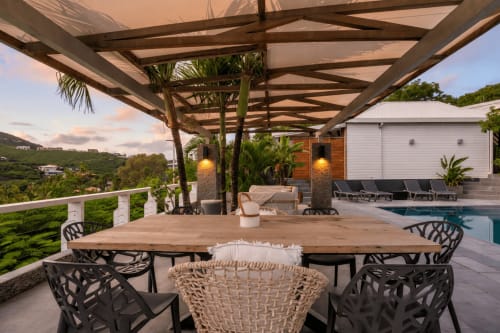 Terrasse de villa de luxe avec table à manger en bois, pergola, plantes tropicales et vue sur mer vers l'île de Saint-Martin
