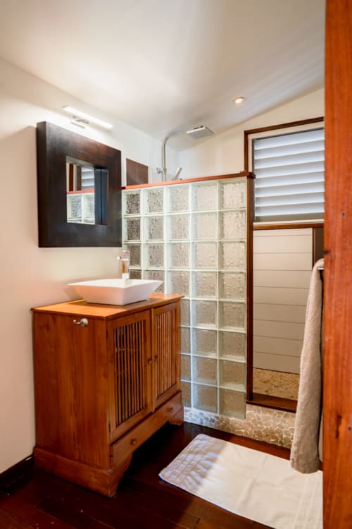 Salle de bain moderne de la villa Les Balcons D'Oyster Pond à Saint-Martin avec meuble-lavabo en bois, lavabo blanc et bloc de verre
