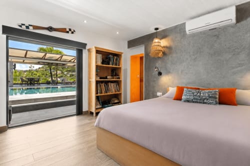 Chambre moderne de la villa Les Balcons D'oyster Pond avec vue sur la piscine, accents orange et mobilier en bois