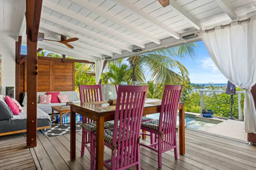 Terrasse de villa en bord de mer aux Balcons d'Oyster Pond, Saint-Martin avec table à manger, chaises violettes, vue mer et palmier
