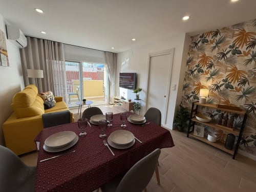 Elegante apartamento frente al mar en Fuengirola con comedor, sofá amarillo y vistas a la ciudad desde el balcón