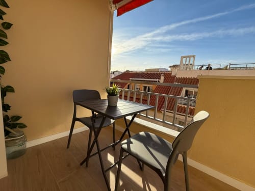 Balcón soleado con mesa y sillas con vistas a los tejados de Fuengirola, elegante apartamento frente al mar de Grupo Inmohouse