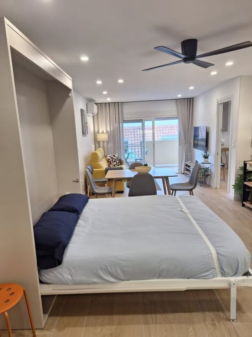 Moderno dormitorio en apartamento frente al mar en Fuengirola con vistas a la ciudad, zona de comedor y mobiliario contemporáneo