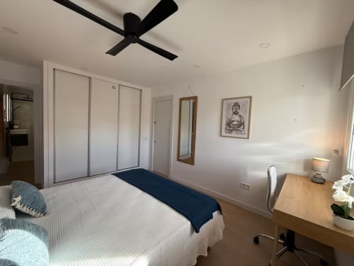 Luminoso dormitorio moderno en apartamento de Fuengirola con cama queen, ventilador de techo, escritorio y vistas a la ciudad