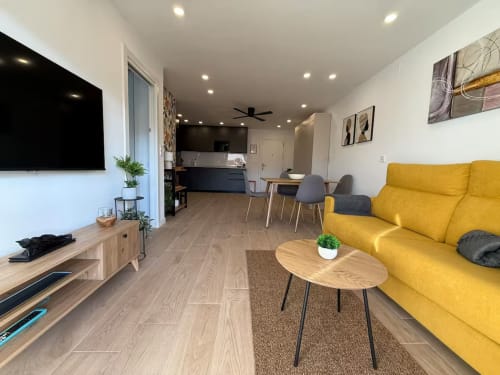 Elegante apartamento en playa soleada en Fuengirola con sofá amarillo, suelos de madera y mobiliario moderno