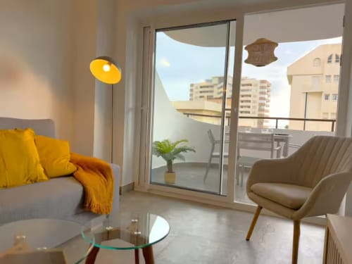 Moderno apartamento soleado en Fuengirola con detalles amarillos, vistas a la ciudad y mobiliario contemporáneo