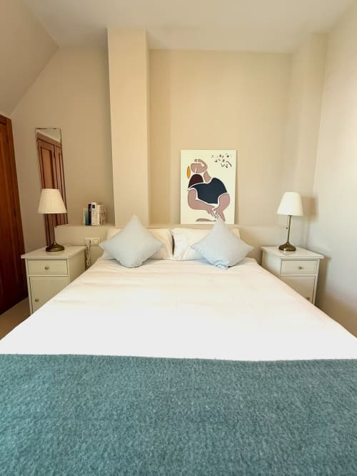 Luminoso dormitorio en apartamento frente al mar en Fuengirola con ropa de cama blanca, acentos azules y decoración moderna