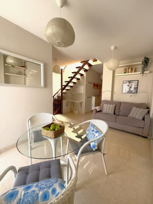 Luminoso ático en Fuengirola con comedor moderno, asientos cómodos y escalera al nivel superior