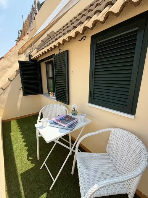 Soleado balcón en apartamento de playa de Fuengirola con silla de mimbre blanca y mesita