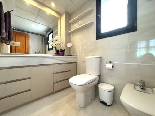 Baño moderno en apartamento frente al mar, Fuengirola. Accesorios blancos, tocador, inodoro y bidé con diseño contemporáneo