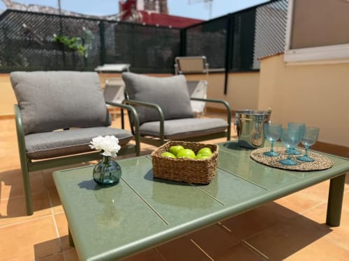 Terraza soleada en la azotea de Fuengirola con cómodos asientos, mesa verde y vistas a las montañas