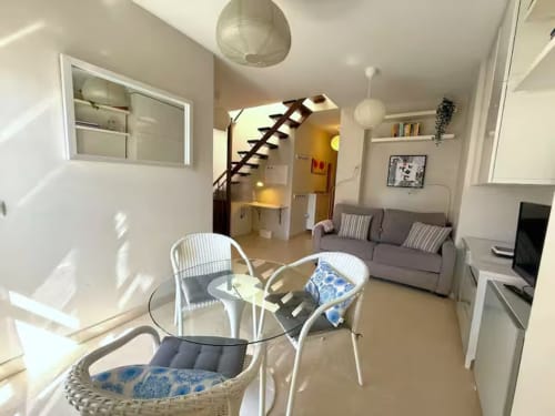 Luminoso apartamento frente al mar en Fuengirola con sala abierta, comedor, escaleras a altillo y mobiliario moderno