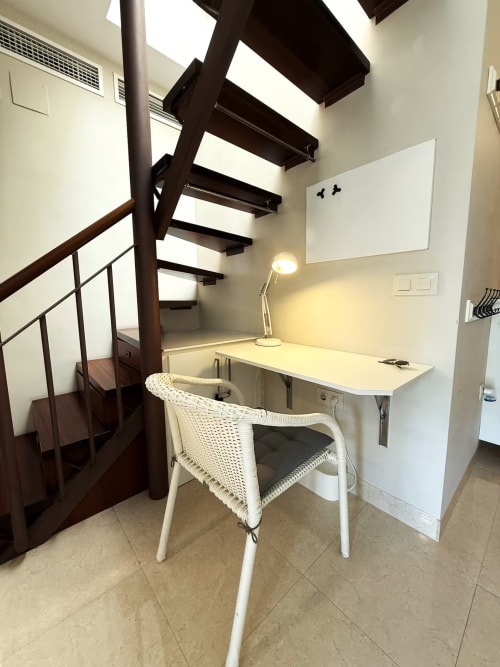 Moderno loft de trabajo en apartamento frente al mar de Fuengirola con escaleras de caracol, escritorio y silla blanca