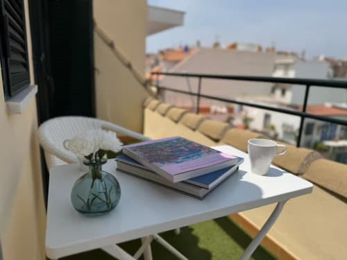 Balcón soleado en apartamento frente al mar en Fuengirola con libros, café y vistas a las montañas costeras