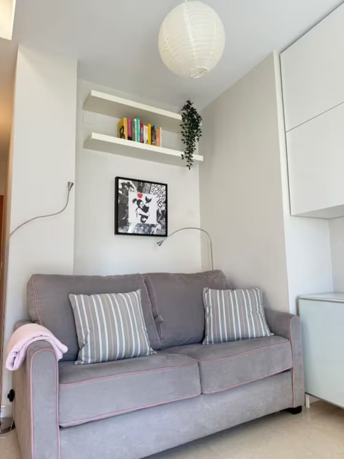 Acogedora sala de estar en Fuengirola con sofá gris, estantes flotantes y decoración moderna