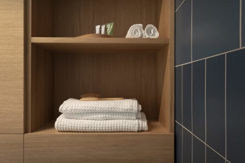 Scaffale in legno per il bagno con asciugamani bianchi arrotolati e articoli da toilette presso Camere d'Aria B&B a Locana