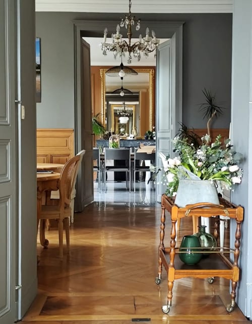 Élégant couloir des Rives De La Tronne avec parquet, lustre en cristal et compositions florales fraîches