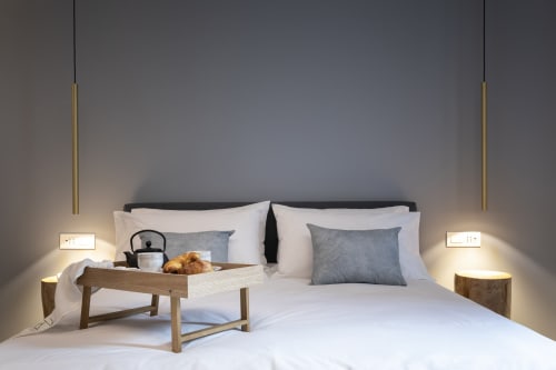 Modern bedroom at Camere d'Aria BnB in Locana with bed, wooden breakfast tray, pendant lights, and grey pillows