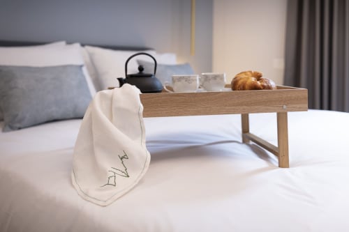 Vassoio in legno con teiera, tazze e pasticcini sul letto della camera d'Aria hotel, Locana